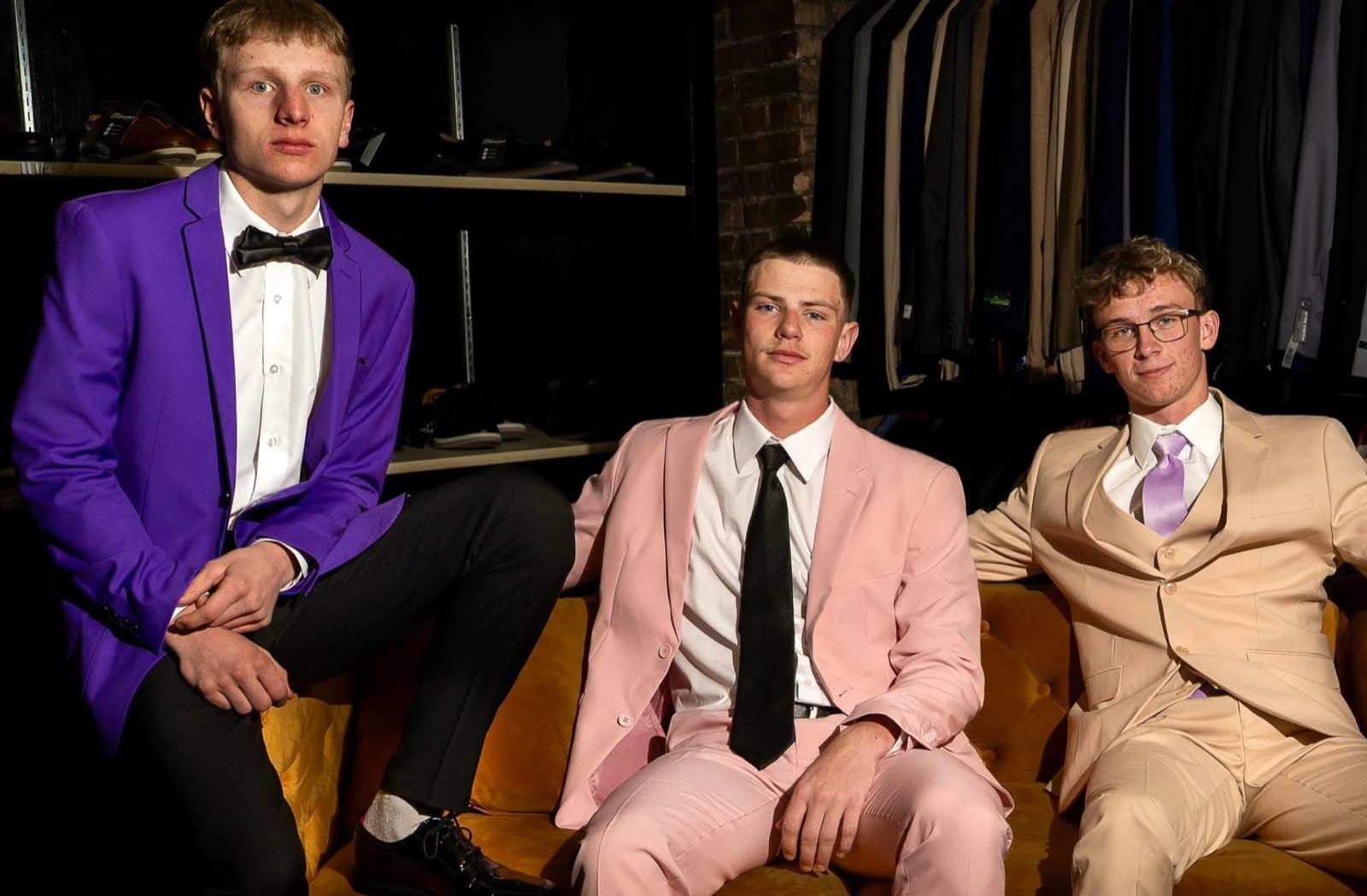 Three young men in prom formalwear on the store’s velvet couch
